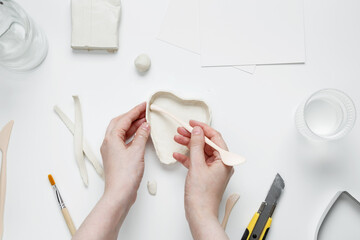 Hobby modeling from clay, tools and accessories for crafting on white background. Woman sculpting...