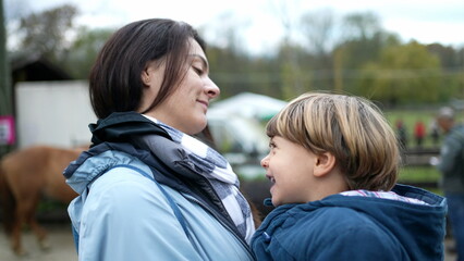 Mother and child bonding outside in authentic real life affectionate moment kissing on the lips and dancing side to side. Mom holding son in arms during fall season