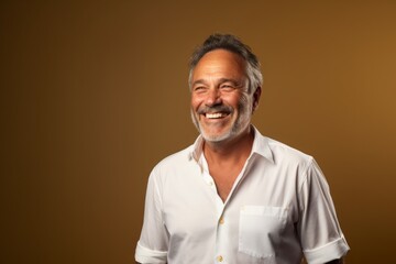 Fototapeta premium Portrait of a cheerful man in his 50s wearing a classic white shirt against a soft brown background. AI Generation
