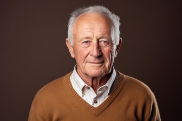 Portrait of a tender elderly man in his 90s wearing a cozy sweater against a soft brown background. AI Generation