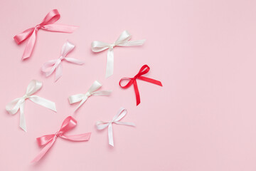 Multicolored bows on pink background. Top view, copy space