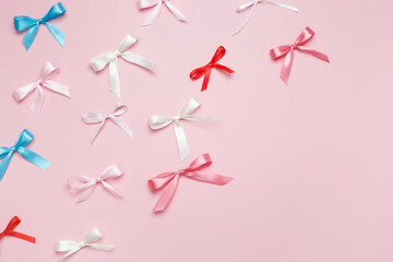 Multicolored bows on pink background. Top view, copy space