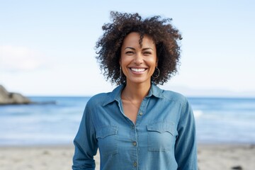 Portrait of a cheerful afro-american woman in her 40s sporting a versatile denim shirt against a peaceful tide pool background. AI Generation