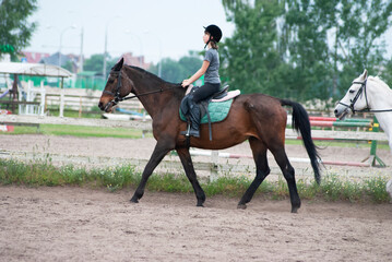 Teenage girl sits upright on horseback