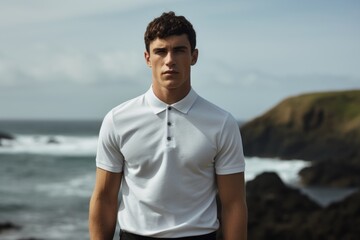 Portrait of a content man in his 20s wearing a breathable golf polo against a rocky shoreline background. AI Generation