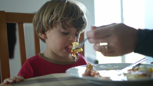 Small boy spitting food out during lunch time. Child not wanting food, feeling disgust