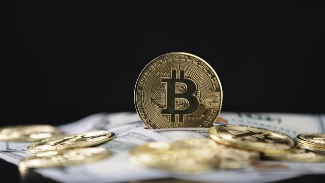 Close-up of metallic shiny bitcoin cryptocurrency coins. Crypto Bitcoin, virtual money and hundred dollar bills. Exchange dollar for bitcoin. Golden Bitcoin.