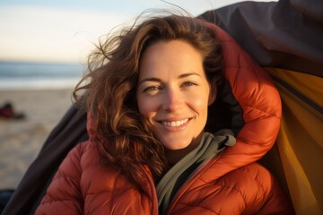 Portrait of a blissful woman in her 30s sporting a quilted insulated jacket against a relaxing hammock on the beach background. AI Generation