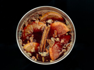 Homemade mulled wine in a pan on a black background