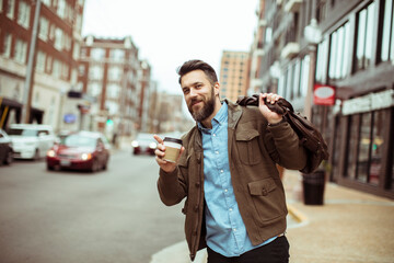 Man with beard holding coffee cup on city street