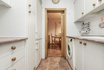 A small kitchen with two walls furnished with white furniture and integrated appliances