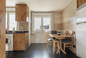 A kitchen with chestnut wood cabinets, black synthetic stone countertops, integrated appliances