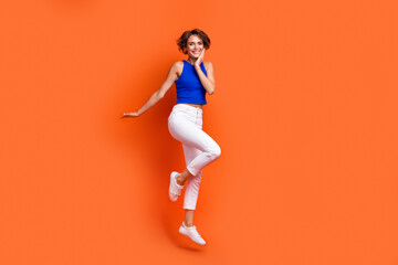 Fototapeta na wymiar Full length portrait of cheerful nice person jumping rejoice empty space ad isolated on orange color background