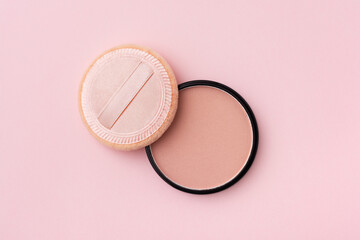 Mineral compact powder and sponge, isolated on a pink background