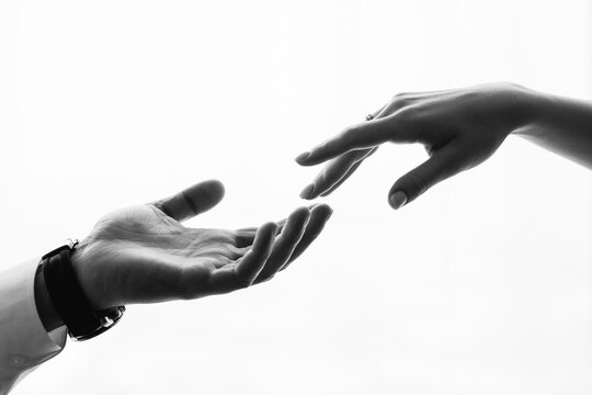 Man and woman touching fingers isolated on white background. Black and white close-up photo. A couple of newlyweds sensually touch each other. Creation of the world