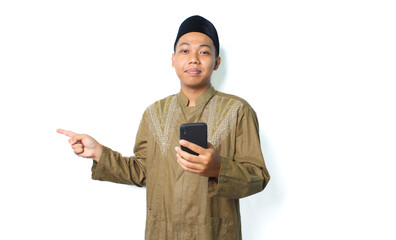 calm asian muslim man holding cell phone pointing to copy space isolated on white background