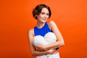 Photo of stunning peaceful person arms hold comfy soft heart symbol cushion isolated on orange...