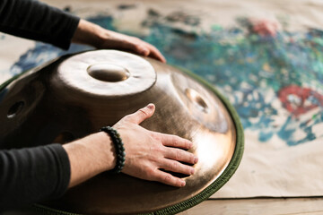 A musician's hand playing the handpan with other people. 