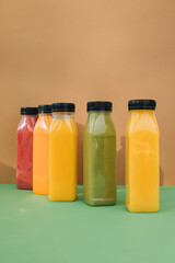 Fruit and vegetable smoothies in transparent plastic bottles. Red, green, orange smoothies on a brown-green background. The concept of healthy eating. Front view