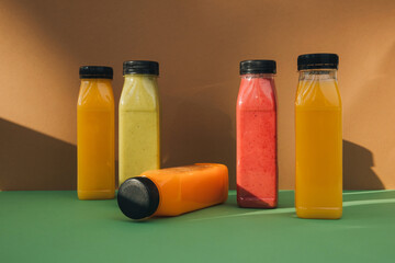 Fruit and vegetable smoothies in transparent plastic bottles. Red, green, orange smoothies on a brown-green background. The concept of healthy eating. Front view
