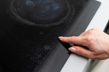 Close up of electric stove control panel, male finger pressing buttons, red LED indicators switched on