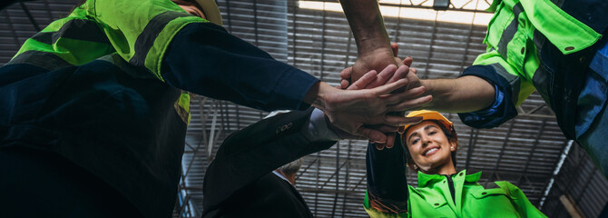 Team engineers and foreman stack hand and shake hands to show success at factory machines. Worker...