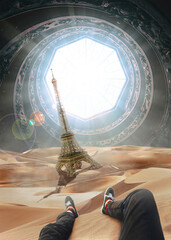 A man sitting and looking a ruined and falling Eiffel tower in a sahara desert drowning in the sands. an tunnel light portail is visible in the sky with metallic strange built circular style.