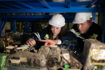 A young female engineer and a male supervisor work together in robotic arm spare parts warehouse,...