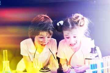 Background with highlights of children of scientists. A boy and a girl are experimenting in the...