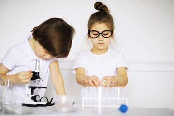 Obraz na płótnie Canvas Two cute children at chemistry lesson making experiments on white background