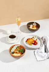 Breakfast spread with omelet, porridge, pancakes accompanied by coffee and sparkling wine