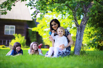 Fototapeta premium Young large family on a summer morning walk. Beautiful mother with children is playing in the park.