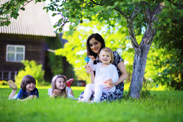 Fototapeta premium Young large family on a summer morning walk. Beautiful mother with children is playing in the park.