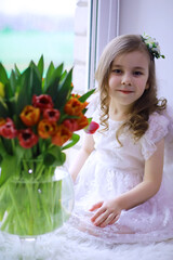 Beautiful girl in white dresses with a magnificent bouquet of the first tulips. International Women's Day. Girl with tulips.