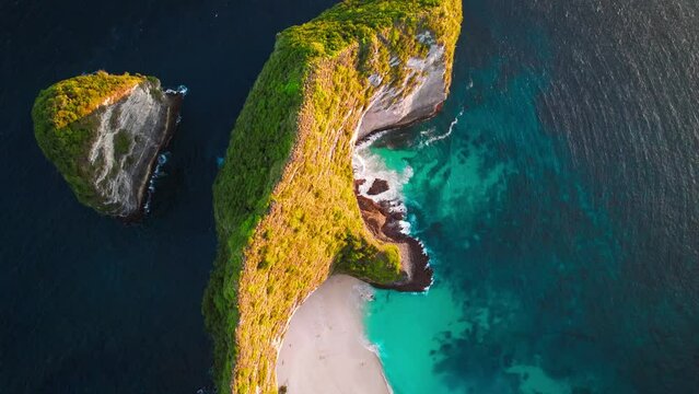 Famous Kelingking T-Rex sightseeing beach landmark at Nusa Penida Island, Bali, Indonesia. Aerial drone footage at sunset with beautiful ocean waves
