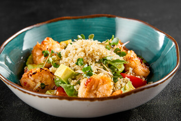 Shrimp and quinoa salad with avocado and tomatoes, served in a turquoise bowl