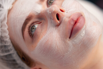 Naklejka premium close-up of a girl's face with a cream or mask during a cosmetic procedure in a beauty salon