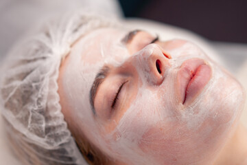 Naklejka premium close-up of a girl's face with a cream or mask during a cosmetic procedure in a beauty salon
