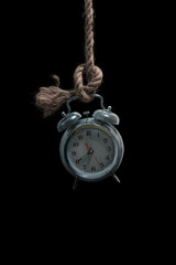 An old classic antique clock hanged with a rope, a mysterious close up of analog round clock hanging in a dark place isolated on black background, cinematic horror style, retro type countdown image. 