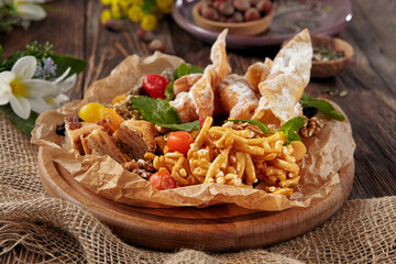 A delightful assortment of Eastern sweets featuring chak-chak, baklava, and khrustiki, arranged rustically on a wooden surface
