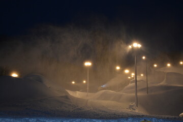 Heaps of snow and blizzards on ski slopes illuminated by lanterns