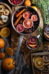 Copper pot of mulled wine with slices of orange, apple, cinnamon, star anise, rosemary and...