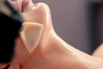 Naklejka premium close-up beautician in gloves applies a mask on the face of a client with a brush care for the skin