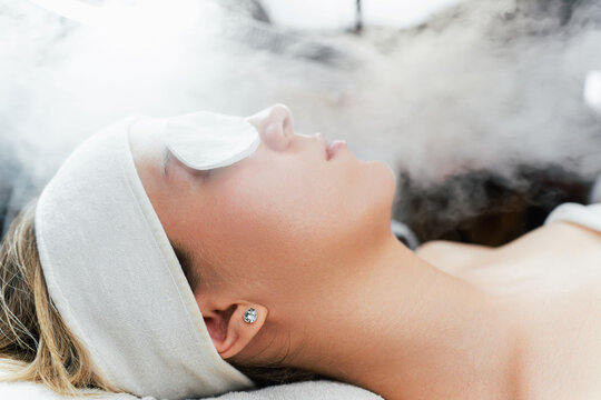 Young woman receiving beauty treatment with thermal ozone facial steamer. Professional cosmetology salon or spa procedure.