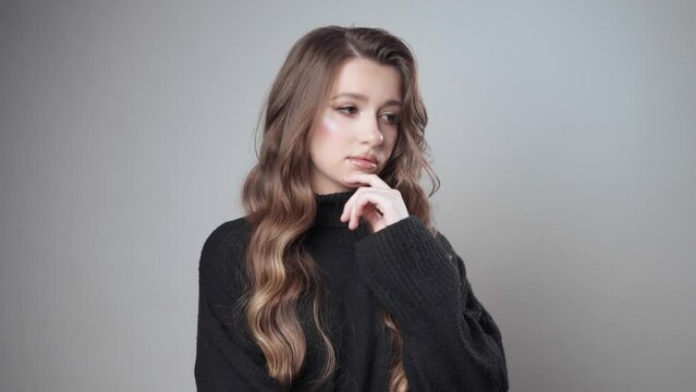 A puzzled girl, immersed in thoughts and doubts, mentally plans something, remembers and calculates tactics and strategy in her head using critical thinking and fact checking.