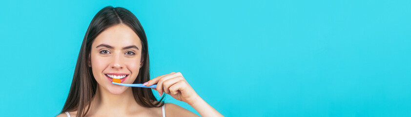Smiling young woman with healthy teeth holding a tooth brush. Young beautiful girl holding a toothbrush. Happy girl brushing her teeth. The concept of a healthy lifestyle. Dental hygiene - obrazy, fototapety, plakaty