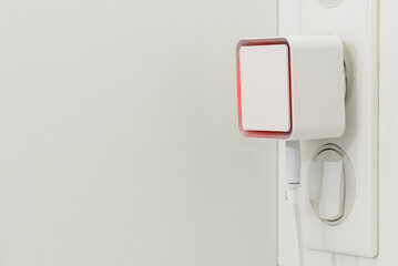 Smart water guard with red alarm turned on against white background. Leak sensor in use.