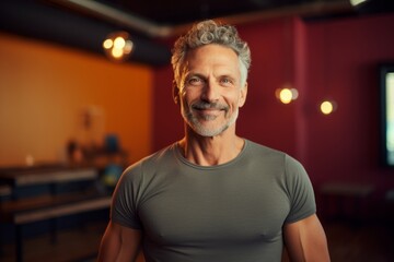 Fototapeta premium Portrait of a happy man in his 50s donning a trendy cropped top against a vibrant yoga studio background. AI Generation