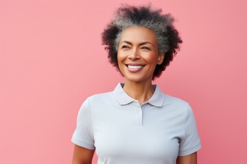 Portrait of a blissful afro-american woman in her 60s wearing a sporty polo shirt against a pastel...