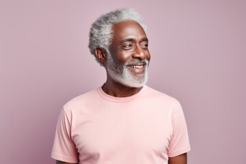 Portrait of a happy afro-american man in his 60s dressed in a casual t-shirt against a pastel or...